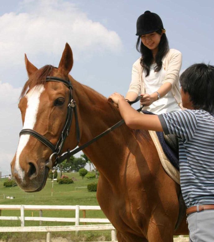 「愛知牧場」で予約すると体験できる乗馬レッスンを満喫する女性