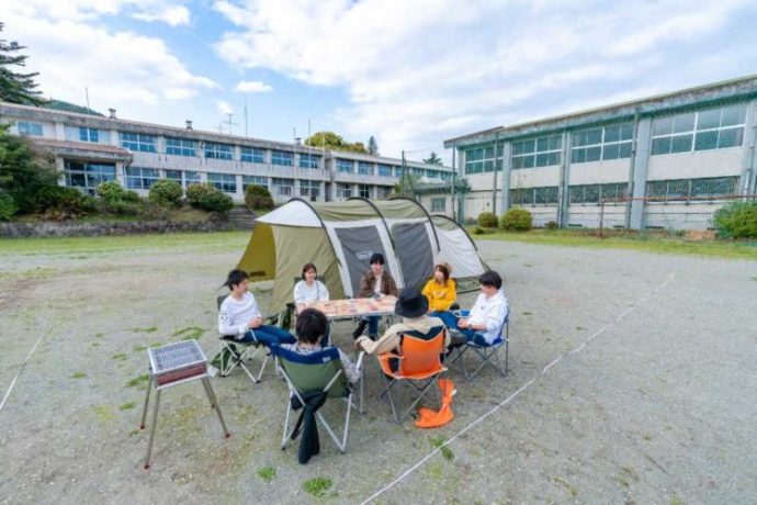 テントサイトのグラウンドでキャンプを楽しむ若者7名