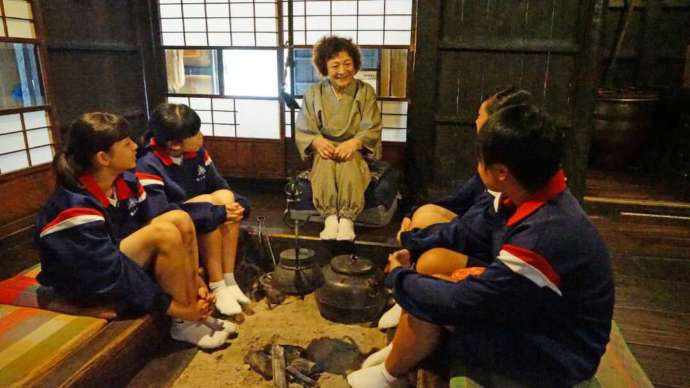 伝承園で囲炉裏を囲んで民話を聞く様子