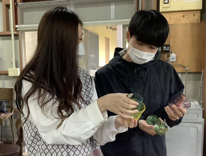 吹きガラス体験で作るコップの色や形を選んでいる2人組の写真