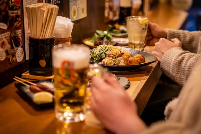 はち八池袋西口店のカウンター席でたこ焼きをシェアするカップル