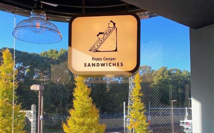 原宿駅にあるHappyCamperSANDWICHESの看板