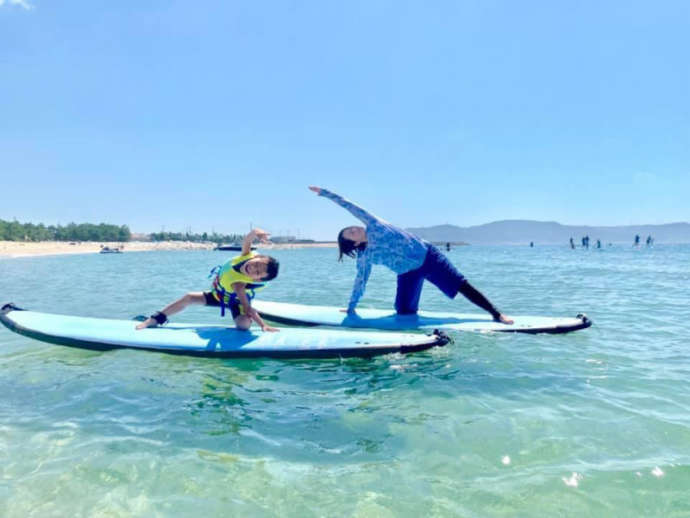 須磨海岸のクリアな浅瀬でSUPヨガのポーズをとる親子