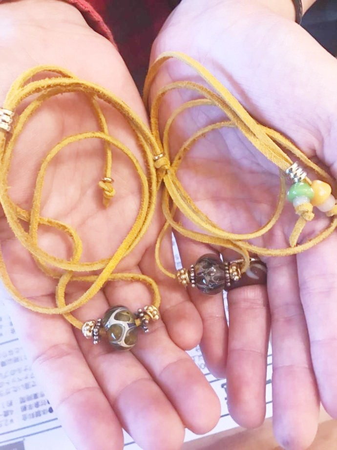 カップルそれぞれの手に乗せられた、お揃いのアクセサリー