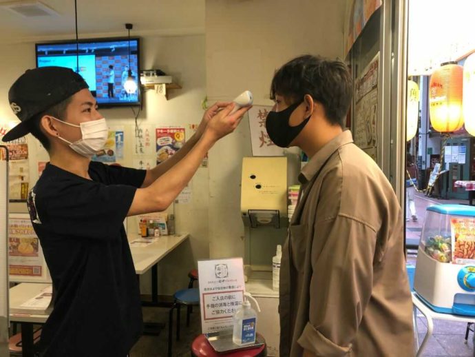『串カツ田中 大宮店』入り口で検温する店員とお客さま