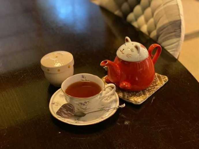 ホットの紅茶と、猫型のポットの写真