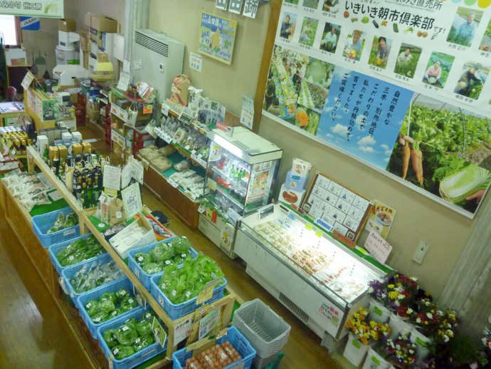 お土産店に新鮮な野菜や特産品、花が並んでいる写真