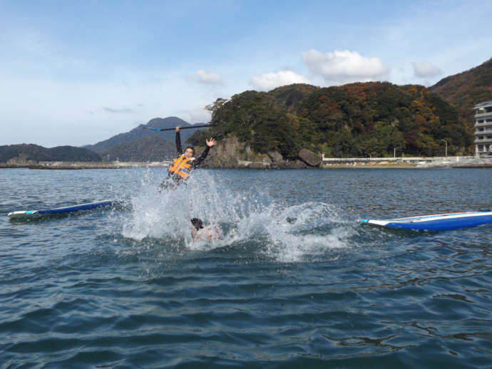 SUPのボードから海に飛び込む人々