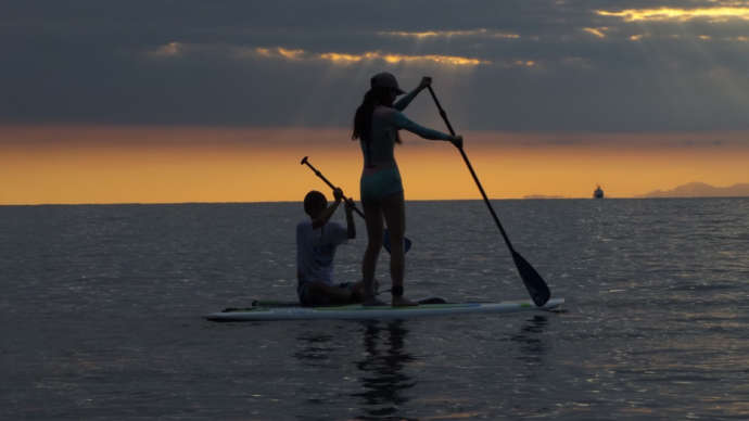 夕暮れの海でSUPをする人々
