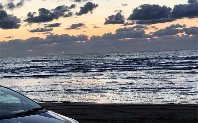 千里浜にあるなぎさドライブウェイの夕焼け空と停車する1台の車の一部