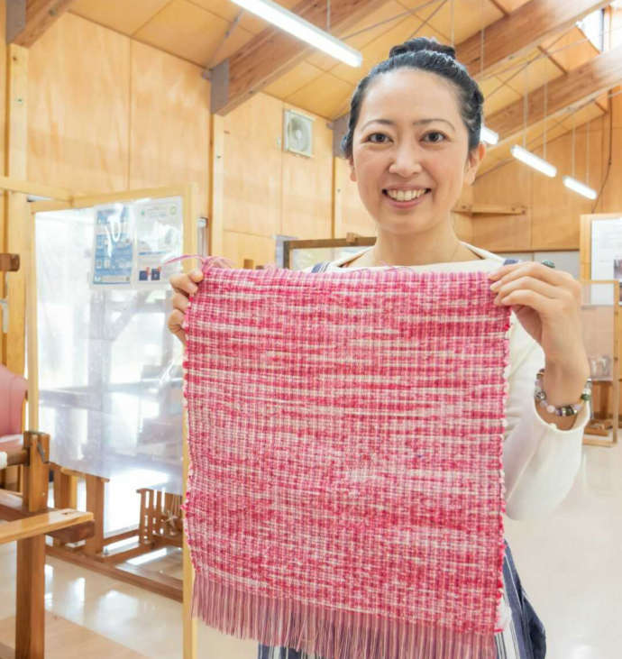 裂織体験で制作した作品を掲げる女性