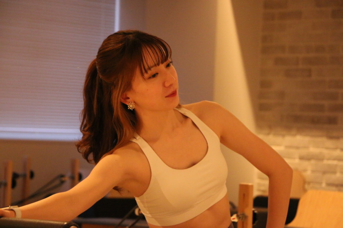 pilates Kでマシンピラティスを行っている女性が右手を横に伸ばしている様子