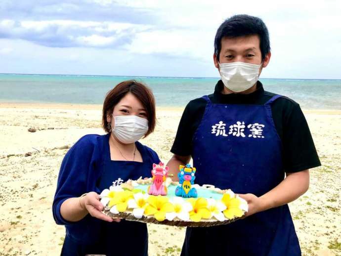 海をバックにして作品と一緒に映るカップルの写真