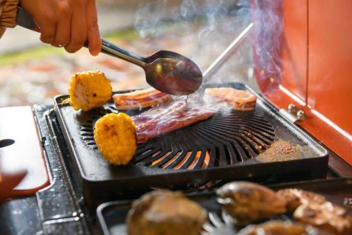 ガーデンバーベキューのコンロで食材を焼く様子