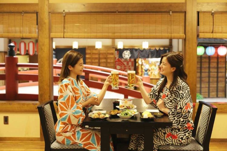 空庭温泉内のレストラン「縄のれん」で乾杯する女性