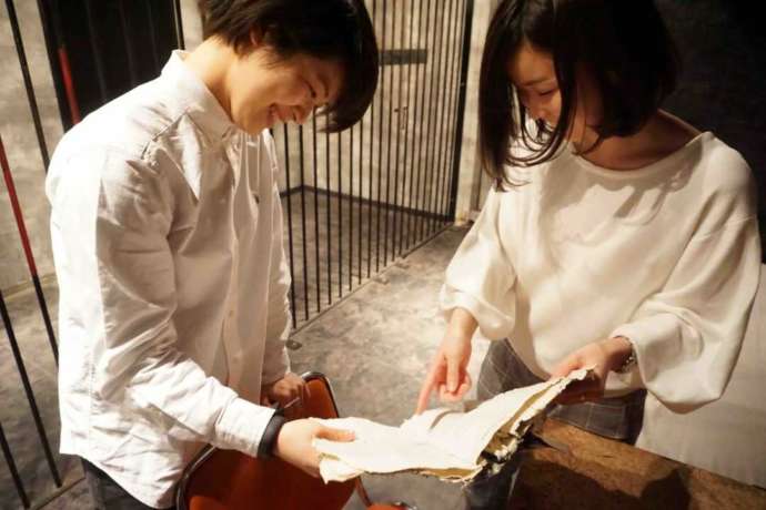 東京都新宿区の「超密室 リアル体験型脱出ゲーム」で脱出するための手がかりを探す女性たち