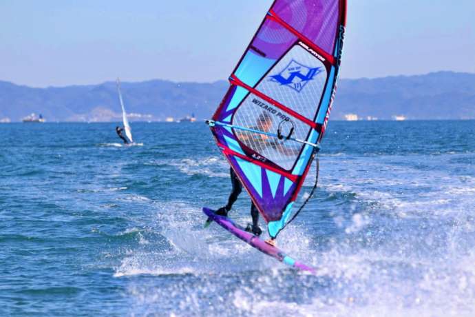 WIND VILLAGEのウインドサーフィン上級者が波しぶきを上げて走っている様子