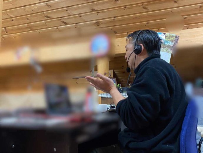 PCの向こうにいる人々に話しかけるウエネウサルみどりのスタッフ