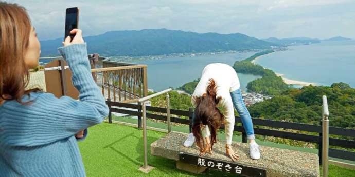 天橋立ビューランドに設置された股のぞき台の上で記念撮影をする女性たち