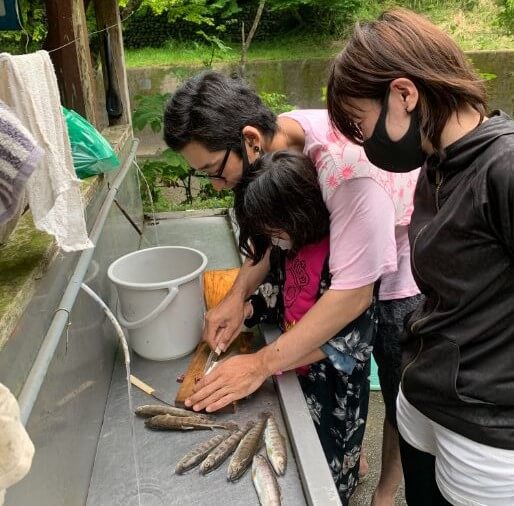やまめ平で自分で釣りあげたヤマメを捌く家族
