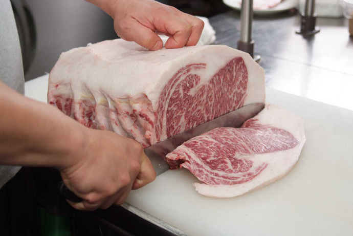 仕入れたお肉を切り分けている焼肉DINING大和 鎌取店のスタッフ